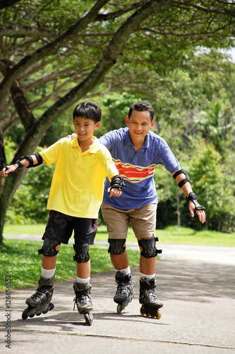 Father and son in park, on roller blades © Alexander