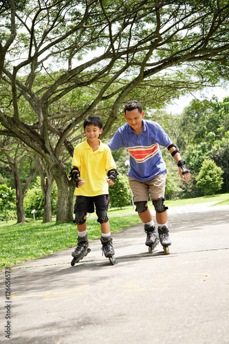 Father and son roller blading in park