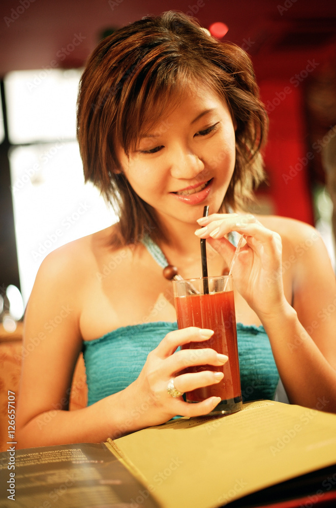 Fototapeta premium Young woman holding drink with straw