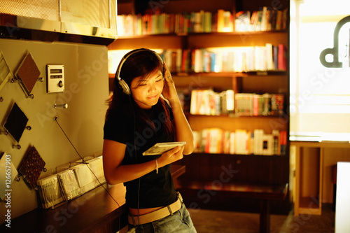 Obraz na płótnie Young woman standing, listening to music, holding CD w salonie