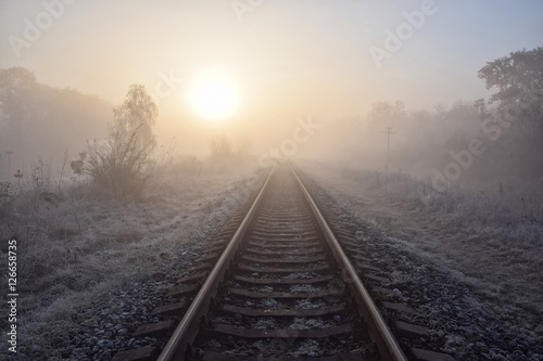 Scenic view of railway going straight ahead to rising sun
