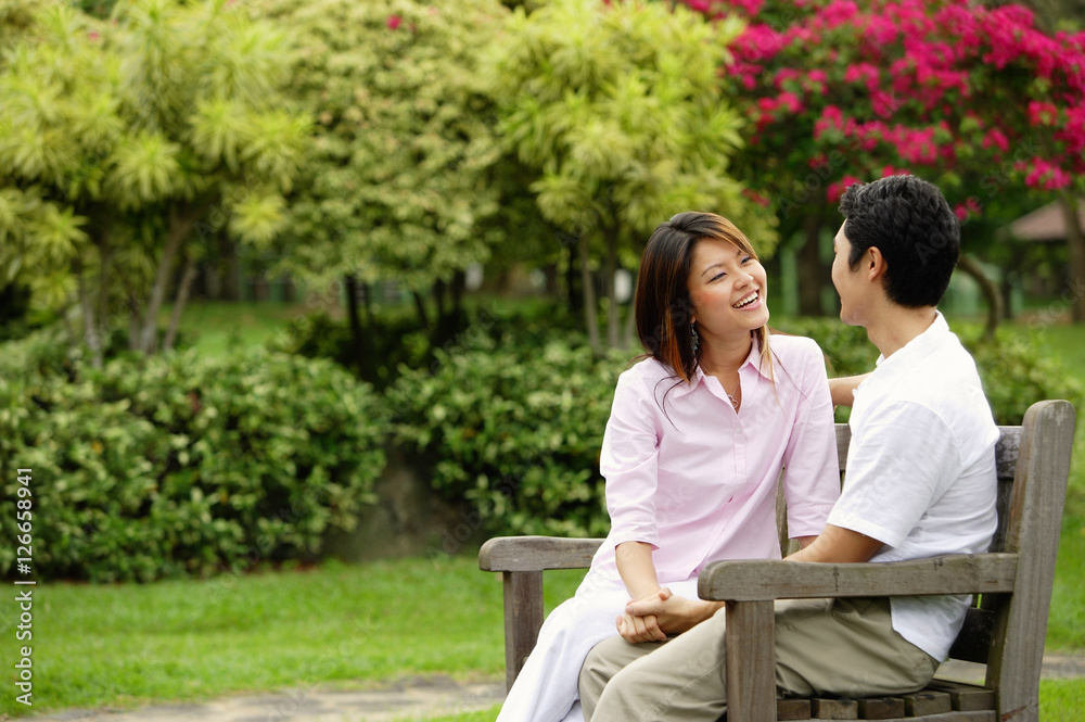 Couple on park bench, looking at each other Couple on park bench, looking at each other