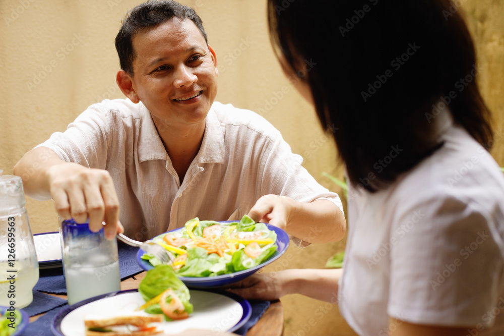 Husband serving wife salad