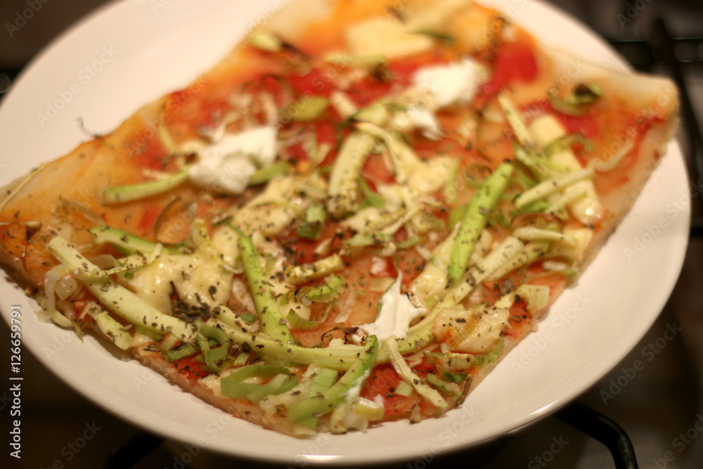 Vegetarian pizza on a plate, with tomato sauce, cheese, zucchini, leek and oregano, baked. Selective focus. Vegetarian pizza on a plate, with tomato sauce, cheese, zucchini, leek and oregano, baked. Selective focus.
