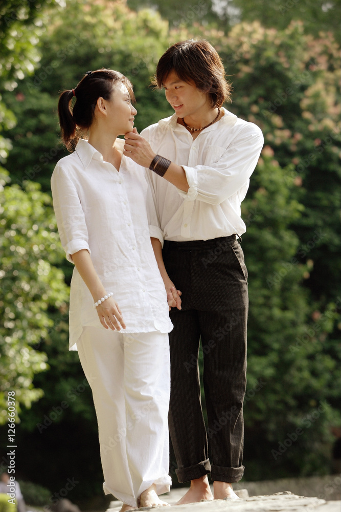 Couple walking hand in hand, man touching woman's face Couple walking hand in hand, man touching woman's face
