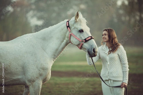 Happy bride is posing with white horse