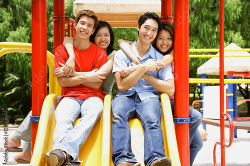 Couples in playground, smiling at camera, portrait