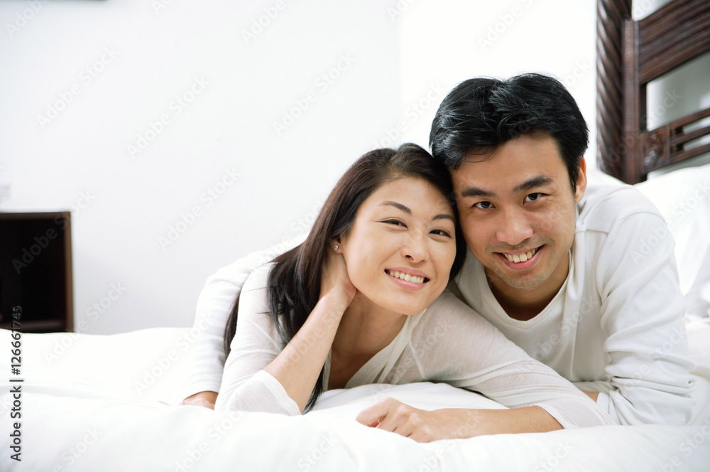 Couple lying in bed, looking at camera Couple lying in bed, looking at camera