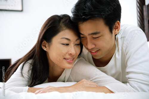 Couple lying in bed, cheek to cheek