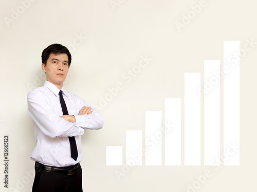 Confident businessman with arms crossed standing over white background with copy space.Young Asian businessman and white bar chart.Success of investment.