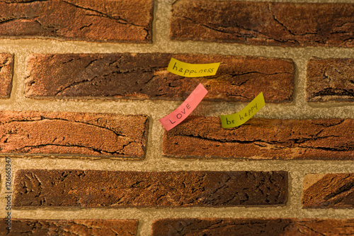 messaggi positivi e motivazionali colorati di felicità e amore attaccati su un muro di mattoni rossi