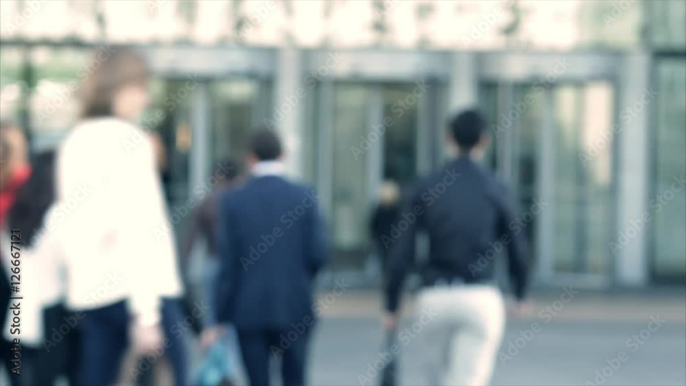 Businessmen crowd near the entry into the business center. People going to work. Concept for finance, job and economy. Modern buildings in business district. Action by day. Focus blur. Toned Businessmen crowd near the entry into the business center. People going to work. Concept for finance, job and economy. Modern buildings in business district. Action by day. Focus blur. Toned