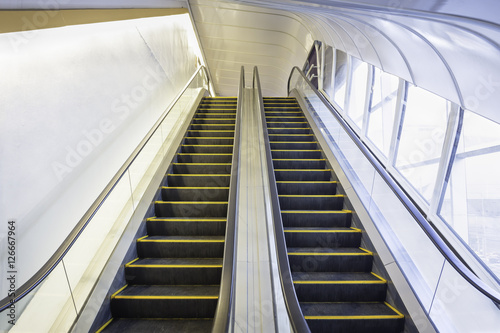 Empty escalator or moving stair. Also called stairway or staircase. Modern architecture design with step, glass for lift people up floor building i.e. shopping mall, airport, metro and subway station.