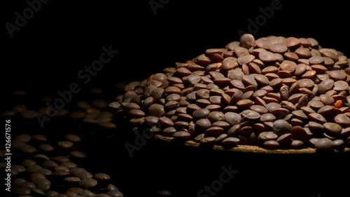 Mountain of lentils legume on a plate gyrating on black background photo