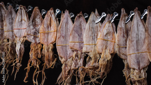Dried squid hanging for sale at local market in Thailand, street food concept