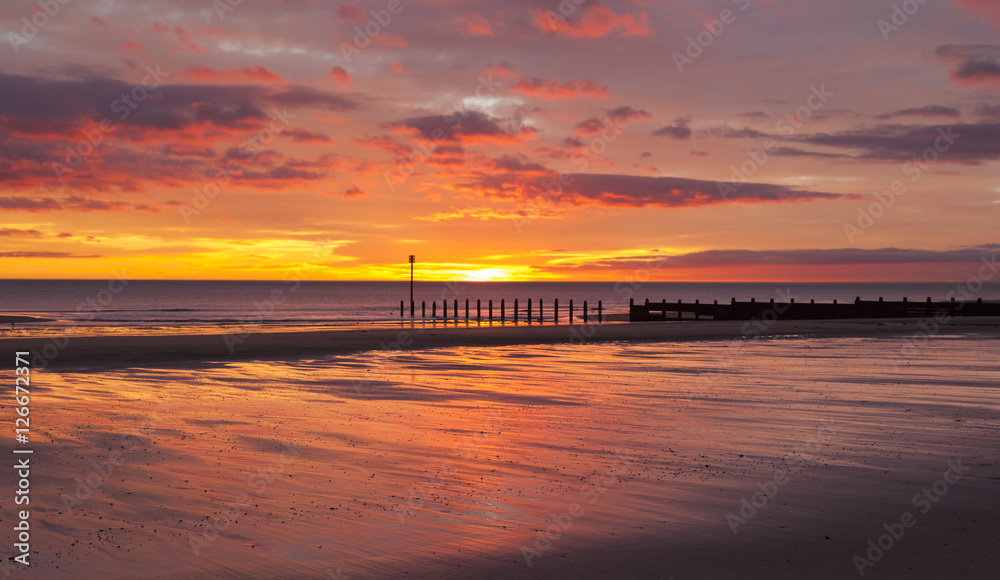 Dawn at South Beach, Blyth, Northumberland. Showing sunrise and groynes on sandy beach.