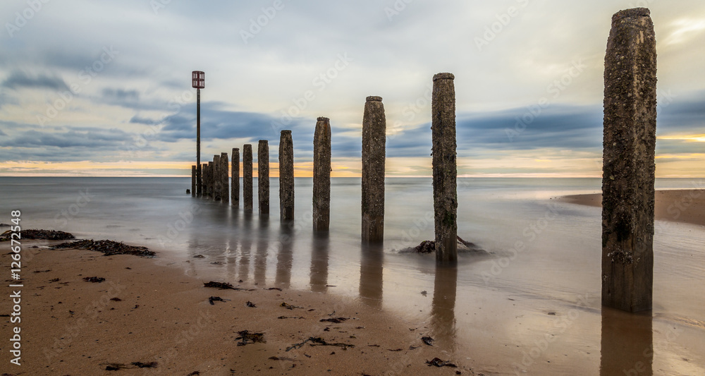 Dawn at South Beach, Blyth, Northumberland. Showing sunrise and groynes on sandy beach.