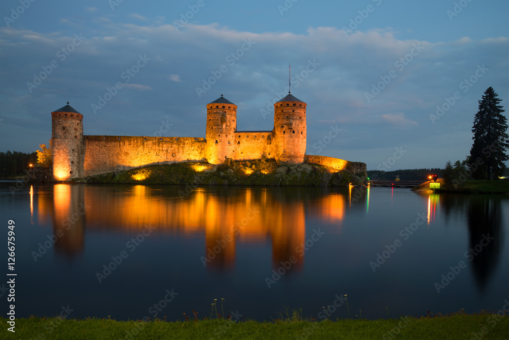 Old fortress of Olavinlinna on the Saimaa lake in night illumination in the August evening. Savonlinna, Finland