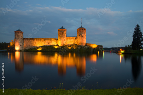 Old fortress of Olavinlinna on the Saimaa lake in night illumination in the August evening. Savonlinna, Finland