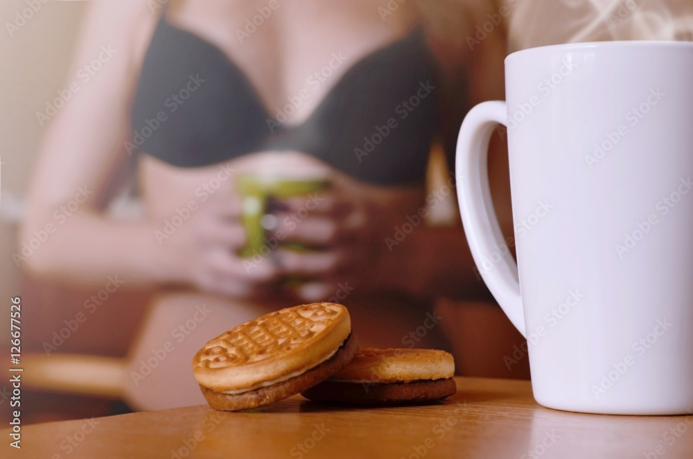A cup of hot coffee and round cookies with a silhouette of a sexy girl in
