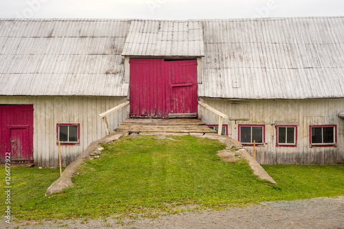 Facade of an old barn with red doors in Gaspe Peninsila, Quebec photo