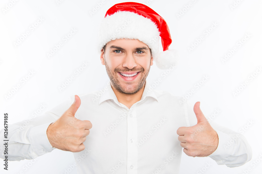 Handsome smiling guy in santa's hat showing thumbs up Handsome smiling guy in santa's hat showing thumbs up