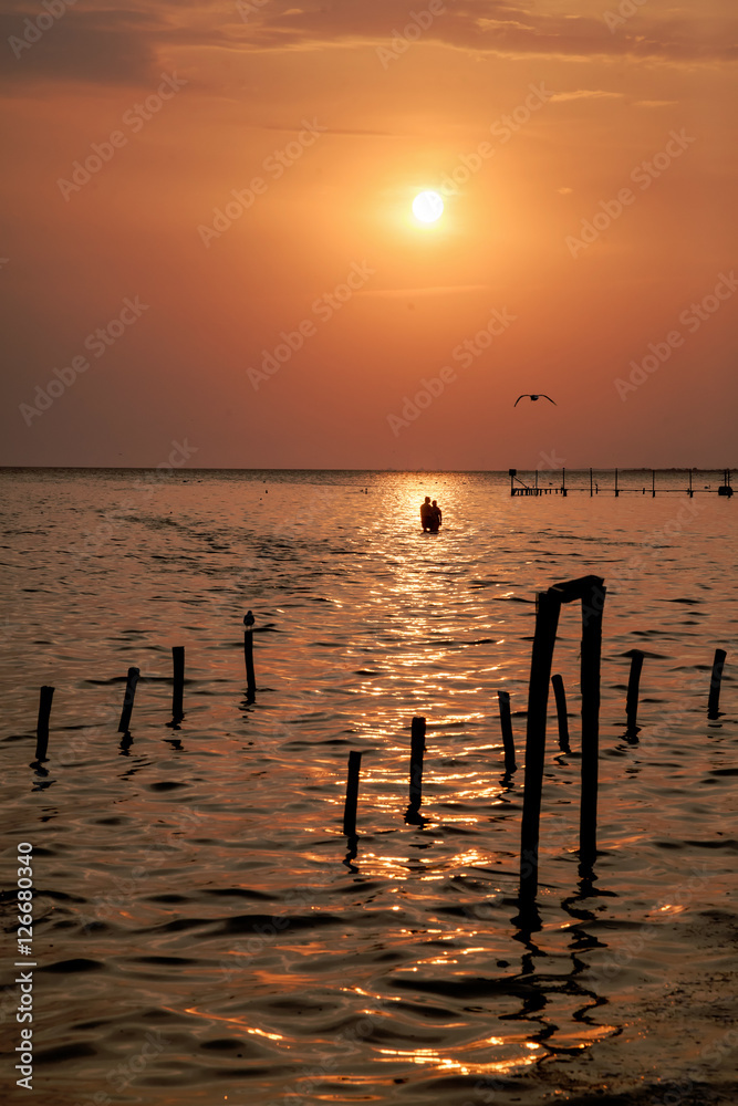 Silhouette of a Couple Standing in the Sea at Sunset Silhouette of a Couple Standing in the Sea at Sunset