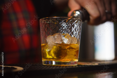 Bartender pours whiskey with ice closeup