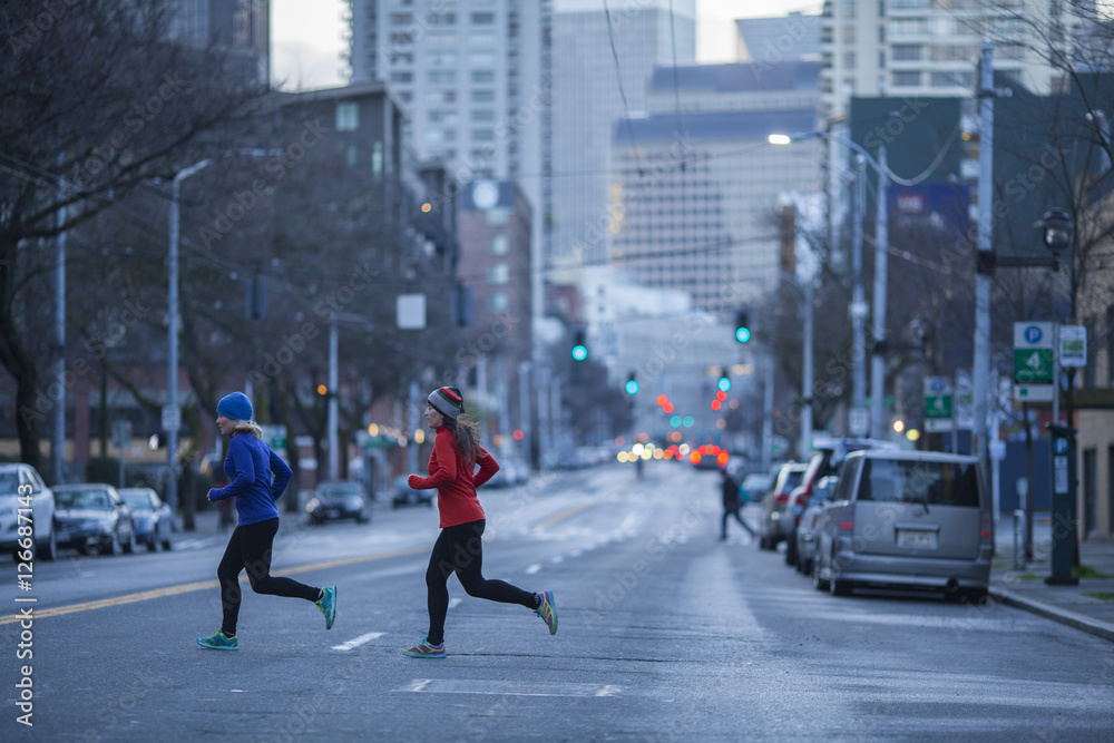 Two adult women running across a Seattle street.  Washington State