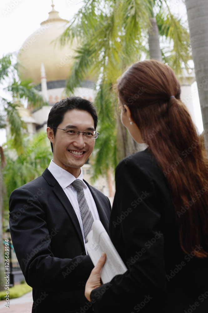 Businessman and businesswoman shaking hands, mosque in the background Businessman and businesswoman shaking hands, mosque in the background