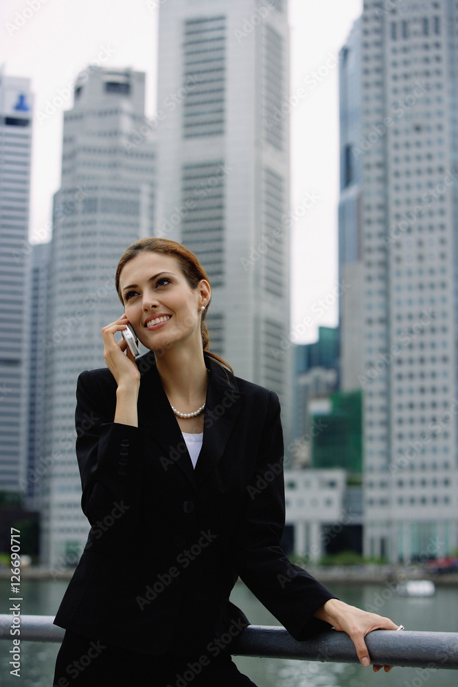 Businesswoman on mobile phone, river and buildings in the background Businesswoman on mobile phone, river and buildings in the background