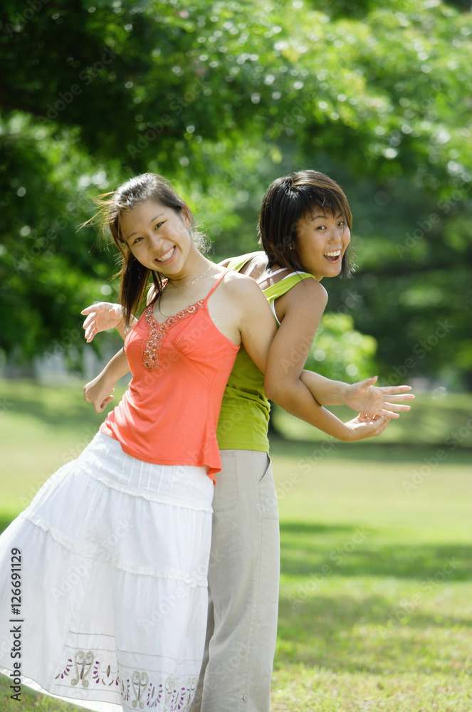 Two young women standing back to back