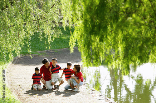Family with three boys outdoors in park, tree branches in foreground