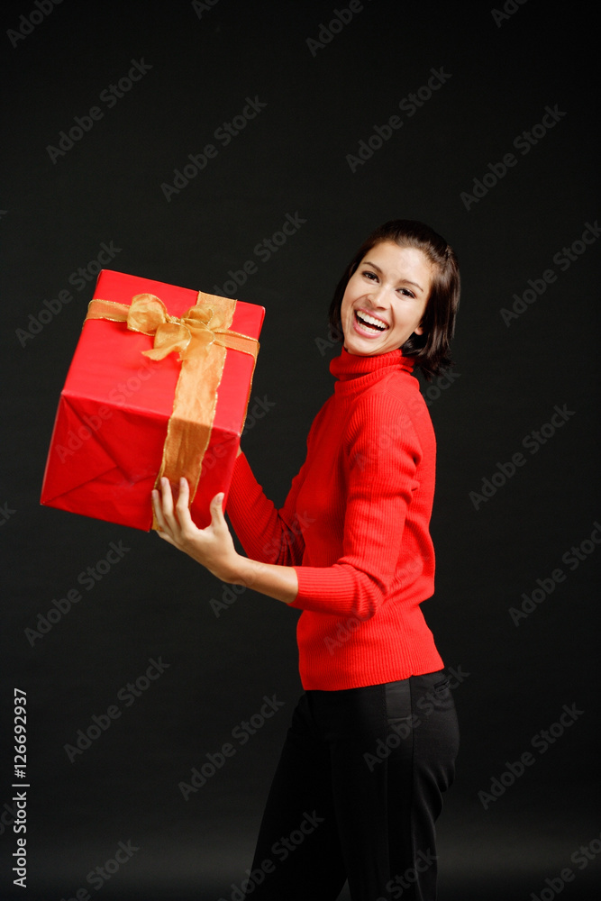 Woman in red turtleneck carrying big red box with gold ribbon Woman in red turtleneck carrying big red box with gold ribbon
