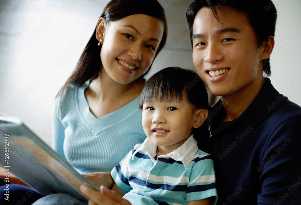 Family smiling at camera, father holding a book Family smiling at camera, father holding a book
