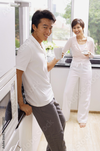 Couple in kitchen, having coffee, smiling at camera