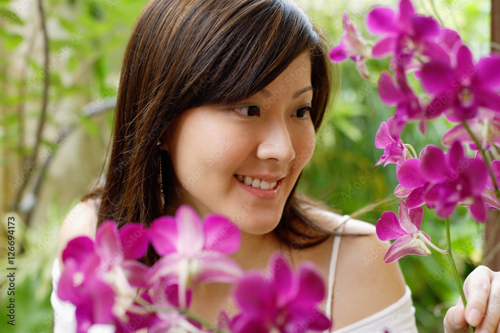 Naklejka premium Young woman looking at orchids
