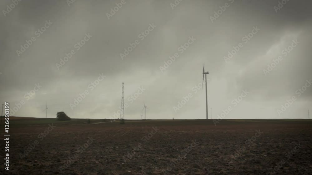 Camera slide over landscape with wind turbines and plowed soil on the empty field at the end of autumn