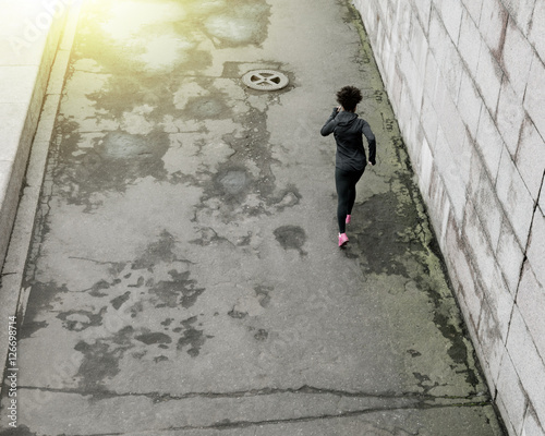 High angle view of young female runner running along city street