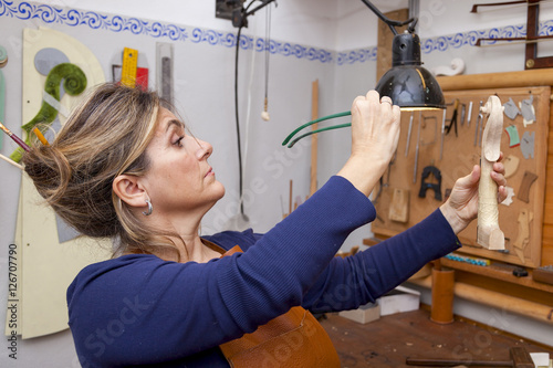 portrait of female mature violin maker while testing the violins