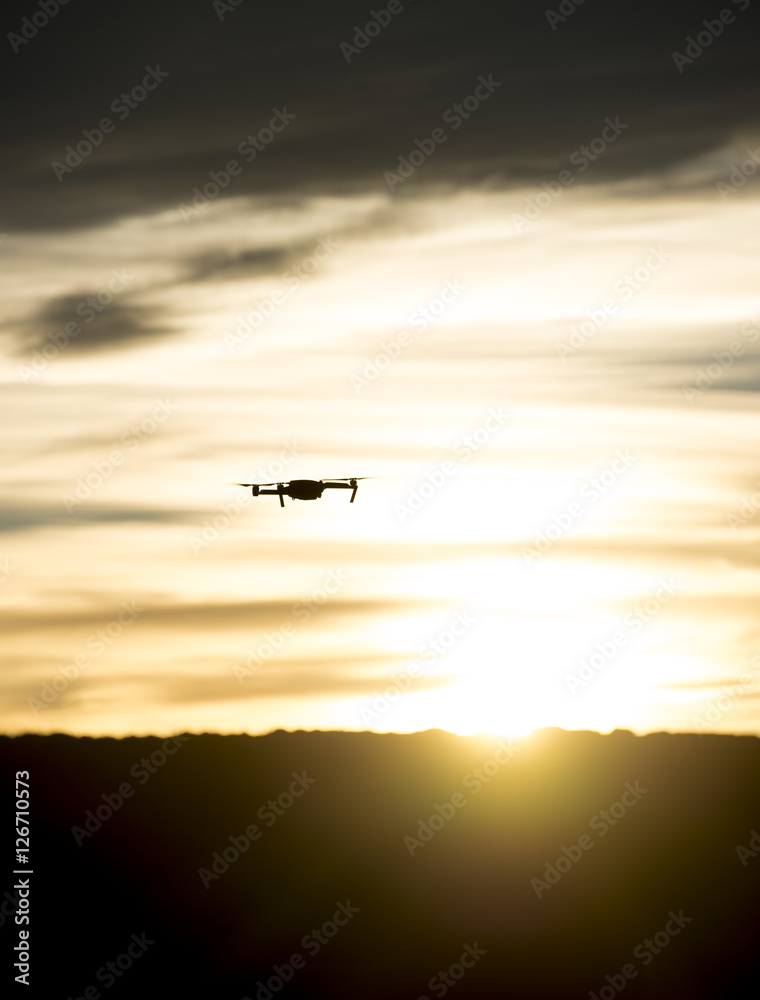 Modern drone silhouetted against sunset