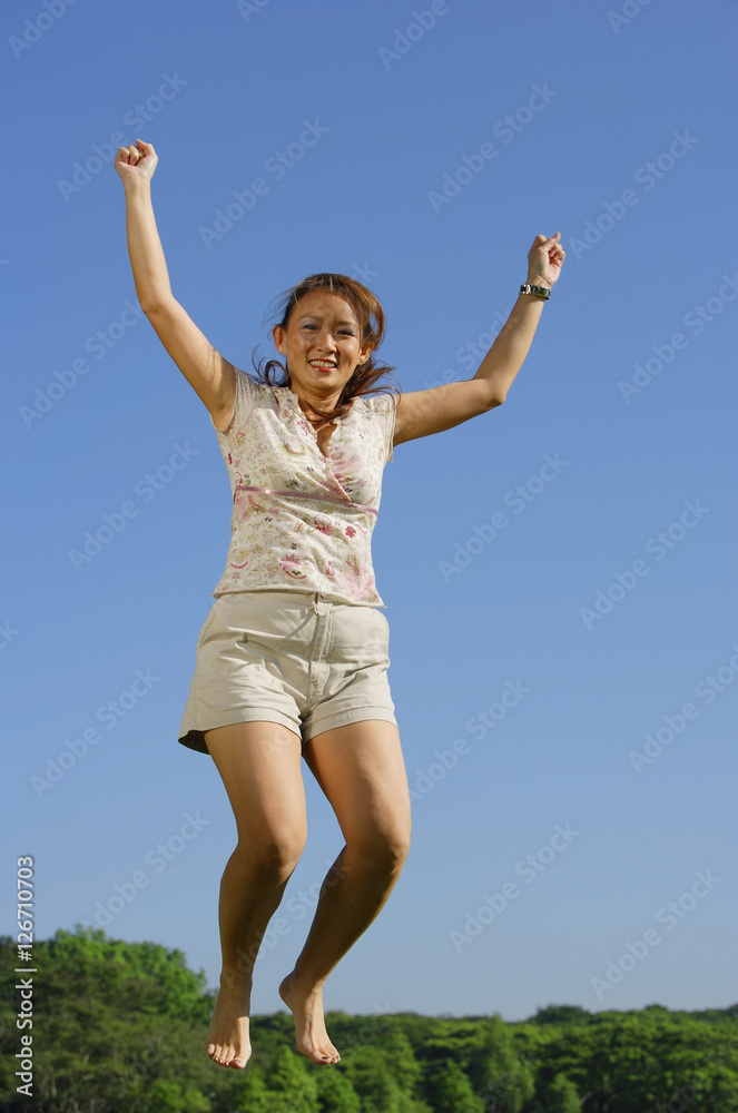 Woman jumping in mid air, smiling at camera Woman jumping in mid air, smiling at camera