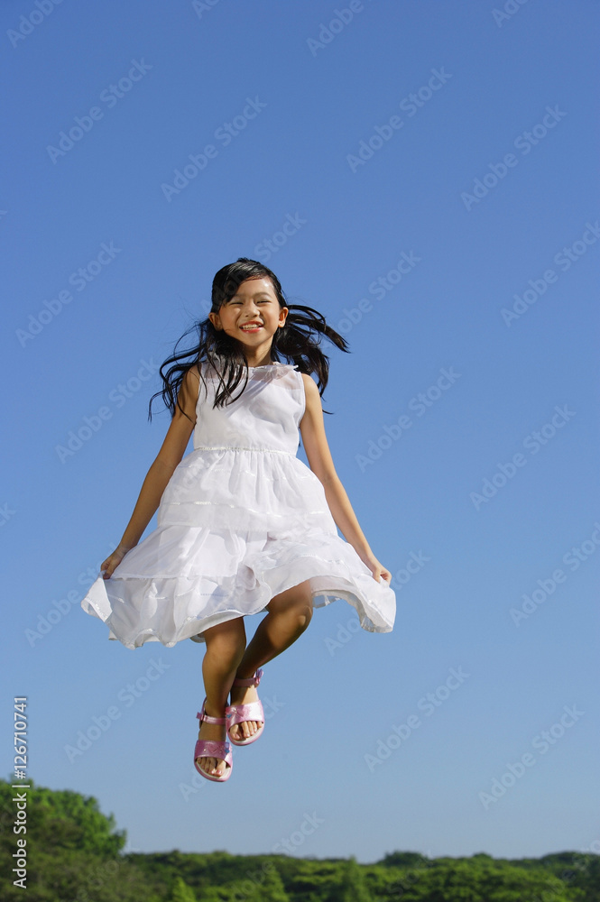 Girl wearing white dress, jumping in mid air Girl wearing white dress, jumping in mid air