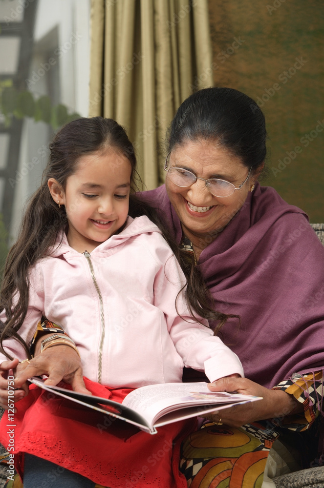 granddaughter sits on grandmother's lap for story (vertical)