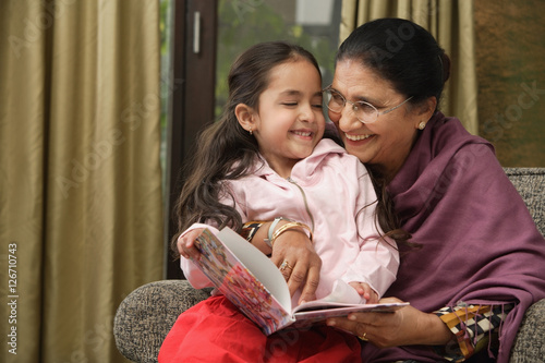 granddaughter sits on grandmother's lap for story (horizontal)
