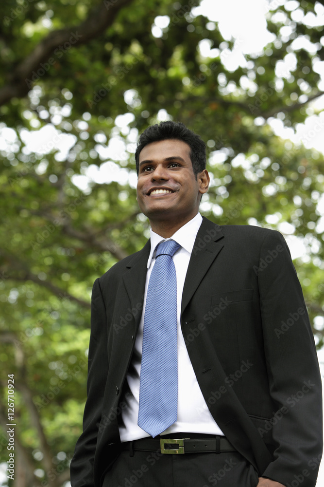 Indian man smiling outdoors with tree in background Indian man smiling outdoors with tree in background