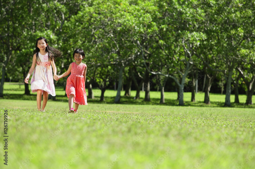 Girls holding hands, walking across park