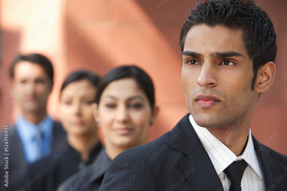 businessman in foreground, three colleagues in background businessman in foreground, three colleagues in background