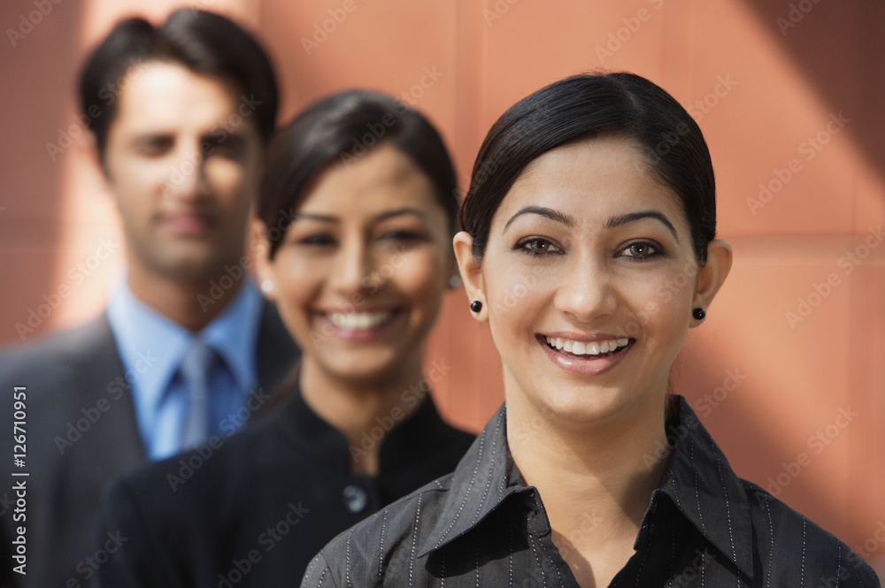 two businesswomen smiling at camera, one businessman (first woman in focus) two businesswomen smiling at camera, one businessman (first woman in focus)