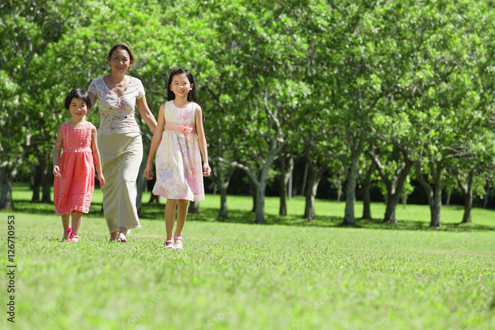 Mother and two daughters walking across field Mother and two daughters walking across field